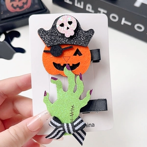 Detail of Halloween hair clips featuring glittery pumpkin and monster hand with festive vibes