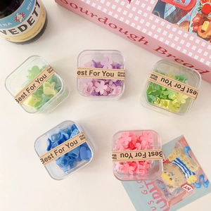 Détail de mini pinces à cheveux fleurs colorées dans cinq boîtes de rangement transparentes