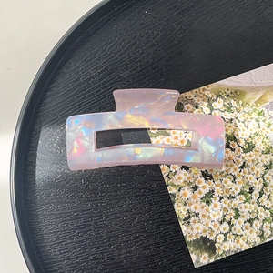 Macro detail of iridescent geometric acrylic hair claw clip with colorful refraction
