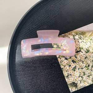 Iridescent pink rectangular hair claw clip detail on a black textured tray