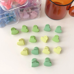 Détail de mini pinces à cheveux mates en forme de cœur sur une surface blanche