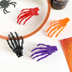 Détail des pinces à cheveux main de squelette en rouge orange noir et violet pour Halloween