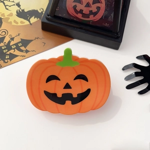 Vue détaillée d'une pince à cheveux citrouille orange avec feuille verte et visage d'Halloween