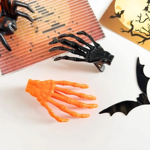 Vue détaillée des barrettes mains de squelette d'Halloween en noir brillant et orange