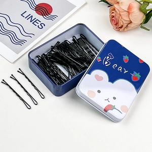 Dettaglio di 50 forcine nere per capelli in una graziosa scatola di latta blu con orso