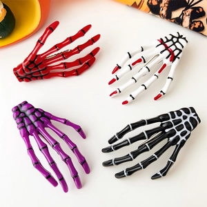 Détail de quatre pinces à cheveux main de squelette colorées pour décor d'Halloween