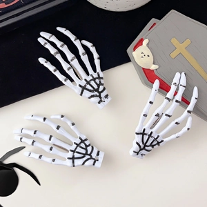 Détail de trois pinces à cheveux main de squelette sur fond sombre décoré pour Halloween
