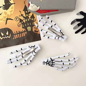 Détail de trois barrettes mains de squelette blanches avec pinces crocodiles en métal