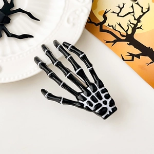 Détail d'une pince à cheveux main de squelette noire et blanche avec décor d'Halloween