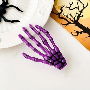 Gros plan d'une pince à cheveux main de squelette violette décor Halloween