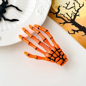 Détail d'une pince à cheveux main de squelette orange vif avec articulations noires