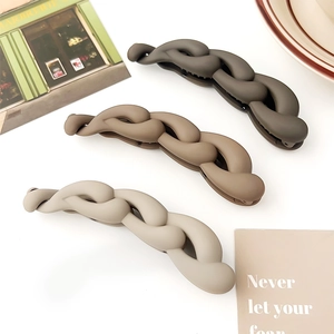 Tre fermagli a banana opachi color moka e beige con design a catena su sfondo minimalista