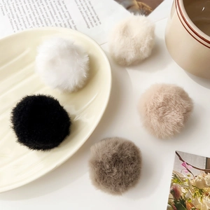 Detailed view of five plush faux fur hair scrunchies in neutral white beige and brown tones