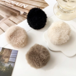 Detail view of plush faux fur hair clips in black white and beige on an aesthetic desk