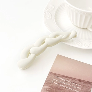 Dettaglio del fermaglio a banana intrecciato crema opaca con decoro in ceramica