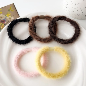 Dettaglio di cinque elastici in peluche morbido in vari colori autunnali su piatto bianco