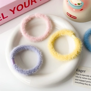 Dettaglio di elastici per capelli in peluche color caramella su un piatto di ceramica bianca