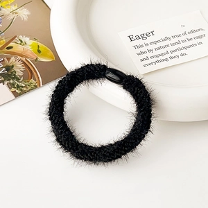 Dettaglio di un elastico per capelli in peluche nero con texture soffice e gancio
