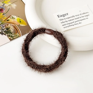 Dettaglio di un elastico per capelli in morbido peluche marrone con fibbia decorativa