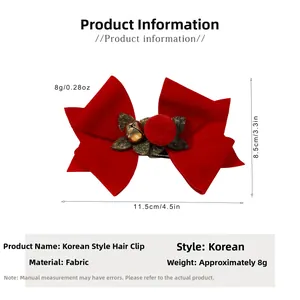 Detail view of 11.5cm red velvet Christmas bow clip with gold bell and green leaf accents