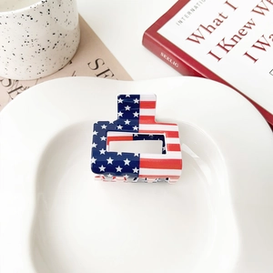 Close-up of square acrylic hair claw clip with American flag pattern on a ceramic plate