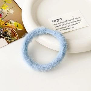 Dettaglio dell'elastico per capelli in peluche azzurro con morbida finta pelliccia