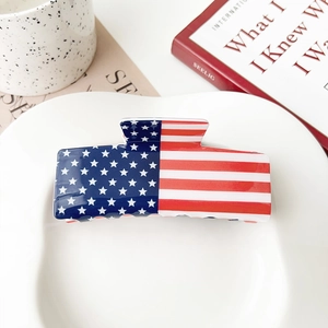 Detailed close-up of an acrylic American flag hair claw clip on a white plate