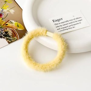 Dettaglio ravvicinato di un elastico per capelli in peluche giallo chiaro su un piatto