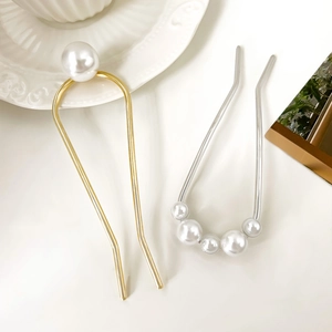 Détail de deux épingles à cheveux en U avec perles en finitions dorée et argentée