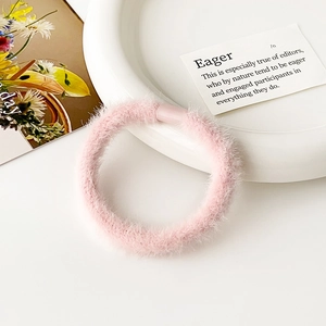 Vista dettagliata di un morbido elastico per capelli in peluche rosa con trama soffice