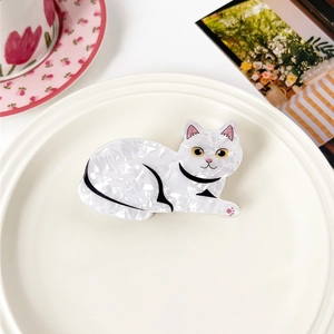 Detailaufnahme einer weißen Katzen-Haarklammer mit Marmortextur auf einem Teller