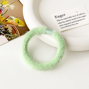 Dettaglio di un elastico per capelli in morbido peluche verde menta su vassoio in ceramica