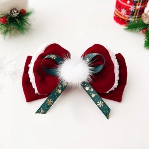 Detail of red velvet Christmas bow hair clip with green snowflake ribbon and soft white fur
