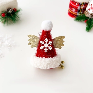 Detail of red Christmas hat hair clip with white snowflakes and gold wings