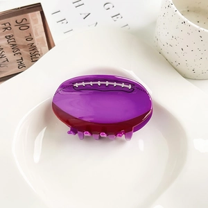 Vista detallada de una pinza para el cabello de acrílico morado con forma de fútbol