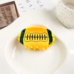 Detalle macro de la pinza de pelo de rugby en acrílico amarillo y verde con costuras