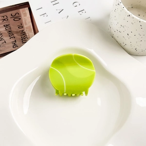 Detalle de pinza creativa para el pelo con forma de pelota de tenis en acrílico verde neón