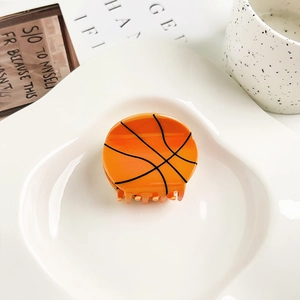 Detalle macro de una pinza de pelo con forma de baloncesto naranja en un plato