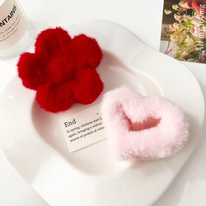 Dettaglio di fermagli per capelli in peluche a fiore rosso e cuore rosa su vassoio