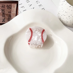 Detalle de la pinza para el pelo con diseño de béisbol y acabado perlado en un plato
