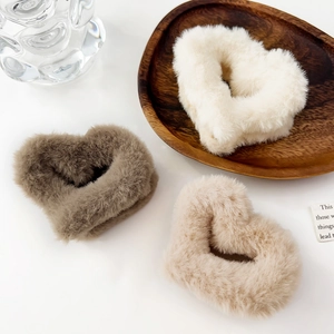 Dettaglio di elastici per capelli in peluche a forma di cuore, toni crema e caffè morbidi