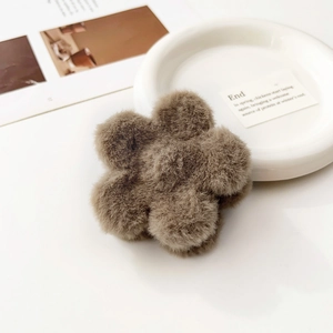 Vista dettagliata della molletta per capelli a fiore in peluche marrone sul tavolo
