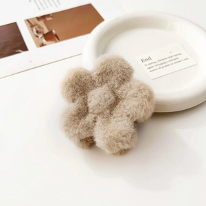 Dettaglio del fermaglio per capelli a fiori in peluche beige su vassoio in ceramica bianca