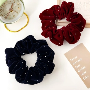 Détail de chouchous en velours bordeaux et bleu marine avec strass argentés et décor