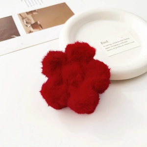 Dettaglio di una morbida clip per capelli a fiore in peluche rosso su vassoio bianco
