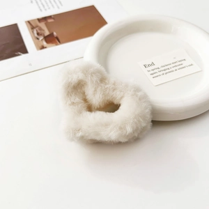 Dettaglio macro di un fermaglio per capelli in peluche a forma di cuore su scrivania bianca