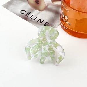 Vue détaillée d'une pince à cheveux pieuvre en acétate marbré vert avec un magazine