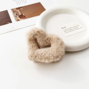 Dettaglio della molletta per capelli a cuore in peluche kaki con texture morbida