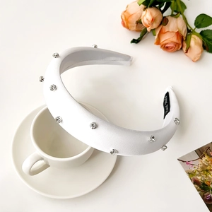 Macro detail of white satin headband with rhinestones and Hand Made inner label