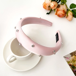 Detailed view of pink padded rhinestone headband with satin finish on a coffee cup